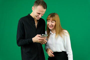 man and woman with gadgets tablet phone in hands on green background talking laugh holding meeting learning to work on Internet flirting relationships flirting couple solving issue positive emotions