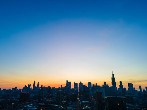 Cityscape Silhouette: A Dazzling Sunset Over the Urban Horizon As the sun gracefully descends, the cityscape stands in silhouette against a canvas of fiery hues. The buildings, 