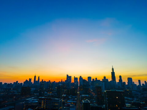 Cityscape Silhouette: A Dazzling Sunset Over the Urban Horizon As the sun gracefully descends, the cityscape stands in silhouette against a canvas of fiery hues. The buildings, 