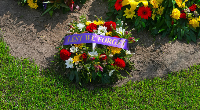 floral wreath with colourful flowers and lest we forget ribbon on grass at ANZAC memorial for Remembrance Day