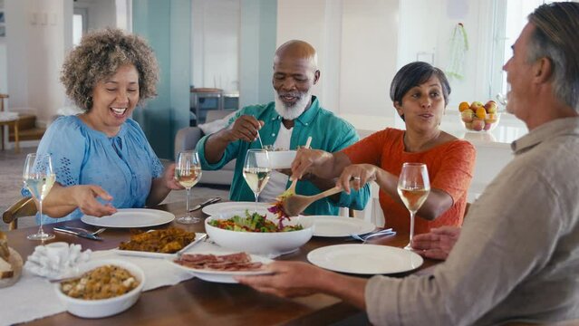 Group of mature friends at home relaxing meeting for lunch with wine - shot in slow motion