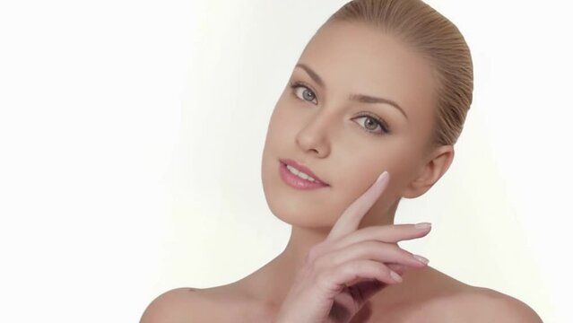 Una hermosa mujer muestra su rostro con piel muy suave y cuidada, su cutis perfecto. Con su mano se acaricia suavemente. Se cuida con cosm&eacute;ticos naturales y ejercicios faciales.