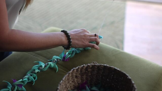 Close-up of a woman making lei in Hawaii, plumeria flowers garland crown handmade.