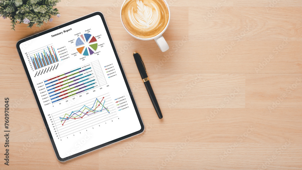 Poster a digital tablet on a wooden desk displaying colorful business analytics graphs alongside a cup of c