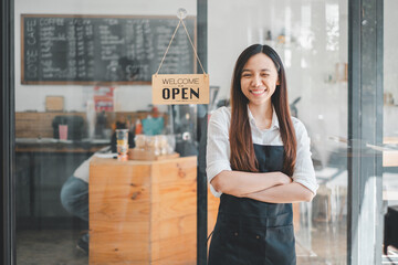 Welcoming cafe owner with arms crossed, smiling in front of her business with an open sign, portraying entrepreneurship and customer service.