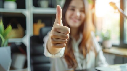 Thumbs up sign. Woman's hand shows like gesture. Home office background