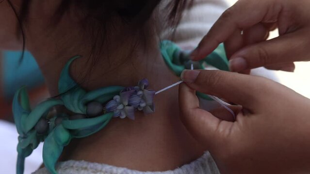 Close-up of a woman making lei in Hawaii, plumeria flowers garland crown handmade.