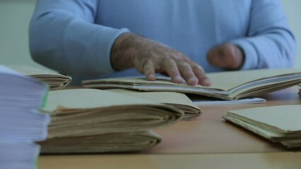 A blind man reads a Braille book with his hands, close-up