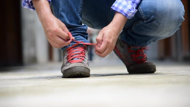Green nature man kneel down and tie shoes on green grass in park. Close up shot of man hands tied shoestring for his construction brown boots.  Close up man hands tie up shoes for footwear concept. 
