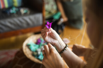 Close-up of a woman making lei in Hawaii, plumeria flowers garland crown handmade.