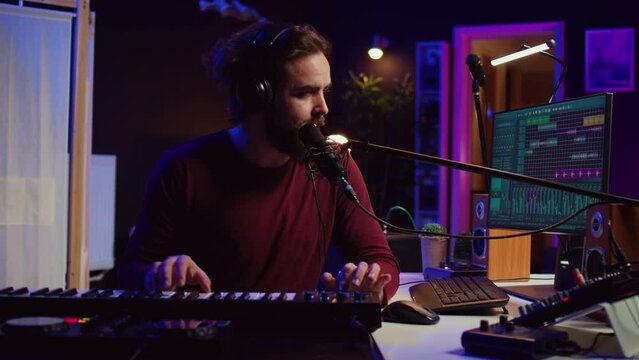 Songwriter recording a new song with microphone and midi controller, playing piano keys in home studio. Talented artist producing music with modern electronic keyboard and tools. Camera B.