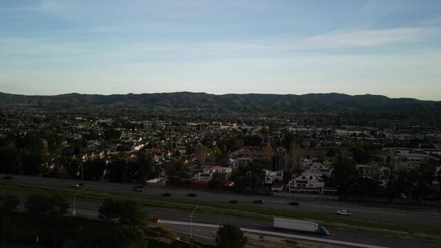 Aerial ascending over Simi Valley California suburbs and hills at sunset on Highway 118