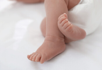 Cute little baby in diaper on bed, closeup