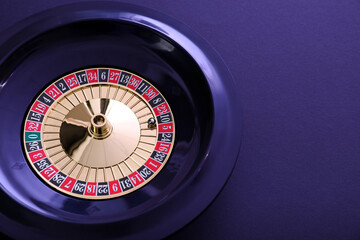 Roulette wheel with ball on dark violet background, top view and space for text. Casino game