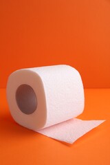 Soft toilet paper roll on orange background, closeup