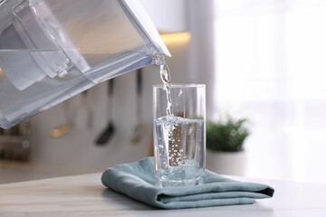 Pouring water from filter jug into glass in kitchen, closeup