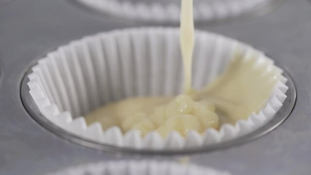 Cake batter pouring into the muffin mold. Muffin cake making at in professional bakery restaurant close up .