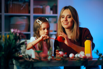 Mother and Daughter Painting Together Red Easter Eggs. Cheerful family having fun doing Easter related activities at home
