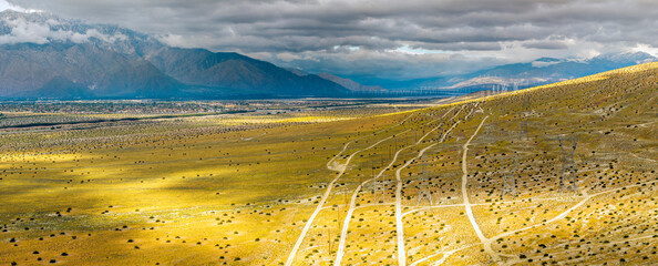 Dappled light from stormy clouds falling on wildflower covered desert hills near Palm Springs