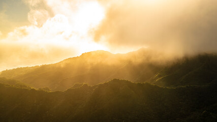 Huge burst of golden sunshine through the clouds above Rarotonga island.