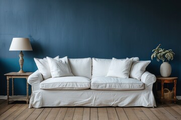 A minimalist interior showcasing a cozy white sofa, lamp, and potted plant against a rich blue wall