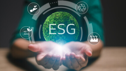 A person is holding a globe with the letters ESG on it