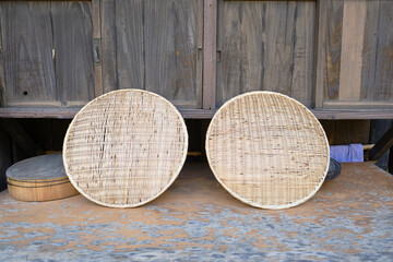 Two Japanese traditional draining baskets made from bamboo being air dried after use outside of a traditional house