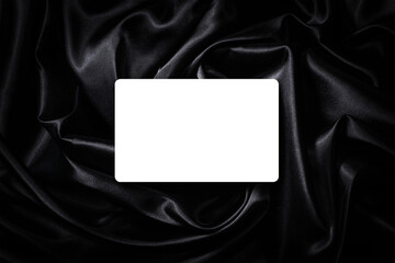 漆黒の黒いサテンの布地の上にある空白のカード