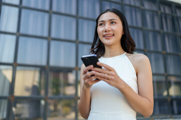Confident and positive Asian online businesswoman using smartphone to relax with mobile application, use business chat and connect with customers outside online market place. Excellent profits.