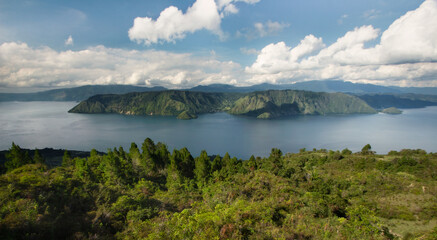Aerial view of volcanic lake Toba and surrounding mountains and  tropical green hills during sunny...
