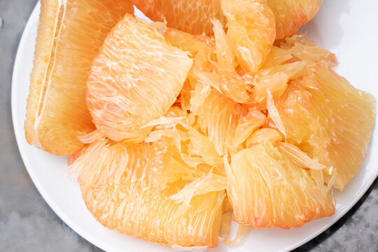 A plate of peeled pomelo pulp on white background. The fruit is famous for digestive supporting function. It is rich in powerful antioxidants like vitamin C, mineral, fiber. Good companion for salad