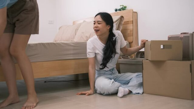 Two female friends are helping unpack items from boxes that were transported by a long-distance shipping company, Two sisters work together to organize their new bedroom before nightfall