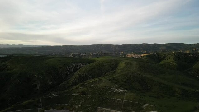 Aerial over rolling green hills in Simi Valley California at sunset