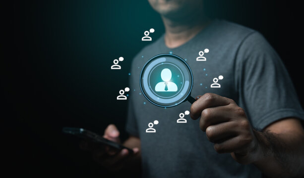 Businessman holding mobile phone and magnifying glass, looking screen with a person in the center. Concept Human resource of searching for employee, possibly a friend or a piece of information