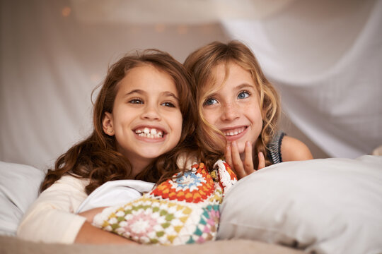 Happy, sleepover and face of children in bedroom for playing, bonding and relax with toys in home. Laughing, friends and young girls on bed in tent or blanket fort for childhood, fun and happiness