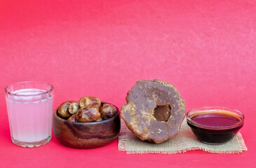 Khejur Ras, Date Palm Liquid Jaggery in a Glass Bowl, Phoenix Dactylifera Fruit and Date Palm Tree Juice Isolated on Red Background with Copy Space, Also Known as Date Palm Sap or Khejur Rosh