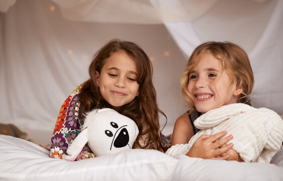 Happy, sleepover and children in bedroom for playing, bonding and relax with toys in home. Night, friends and young girls on bed in tent or blanket fort for childhood, fun and happiness together