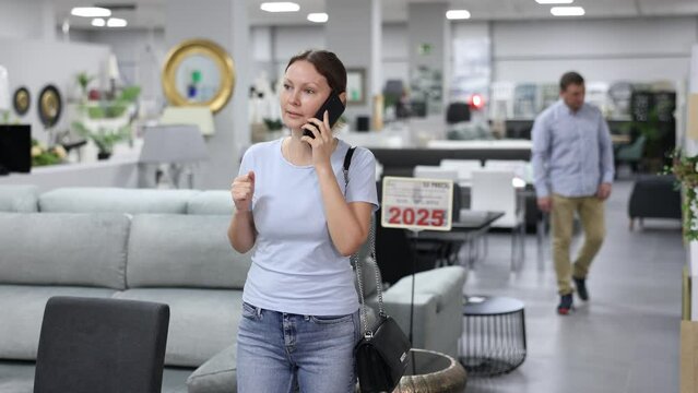 Portrait of attractive woman consulted on phone while looking for new furniture in salon. High quality 4k footage