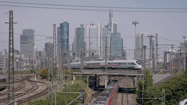ICE train crossing bridge in urban area with city skyline in daylight, clear skies