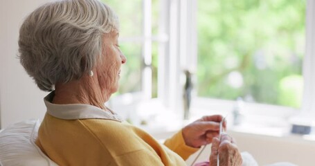 Old woman, knitting and thread with needle for relaxing creativity in retirement for handmade, crochet or hobby. Elderly person, hands and loop yarn in apartment or sweater pattern, skill or craft