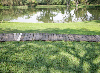 Row of wooden walkways in the garden with a pond in the background