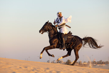 Saudi man in a desert riding his horse