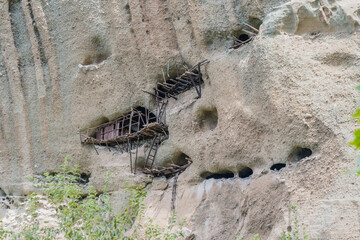 Old wooden ladders cling to the side of an eroded cliff face, in Meteora, Greece