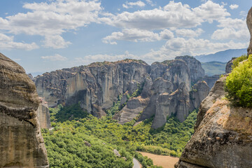 Fototapeta na wymiar Panoramic view of Meteora's rock formations and valleys with lush greenery under a blue sky, in Meteora, Greece