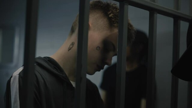 Warden takes off handcuffs from young prisoner. Multi ethnic teenagers serve imprisonment term in correctional facility or detention center. Young criminals in prison cell. Justice system. Close up.
