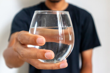 A man in black clothes holding a glass of water