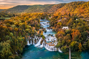 Krka, Croatia - Aerial panoramic view of the beautiful Krka Waterfalls in Krka National Park on a sunny autumn morning with colorful autumn foliage and gold and blue sky at sunrise