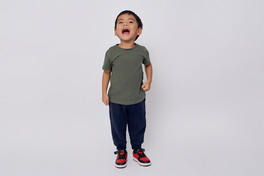 Full body little small smiling happy Asian boy 2-3 years old wearing green t-shirt standing confident while looking at camera isolated on white background