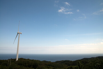 View of the wind turbine on the hill against the sky background