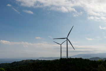 View of the wind turbine on the hill against the sky background